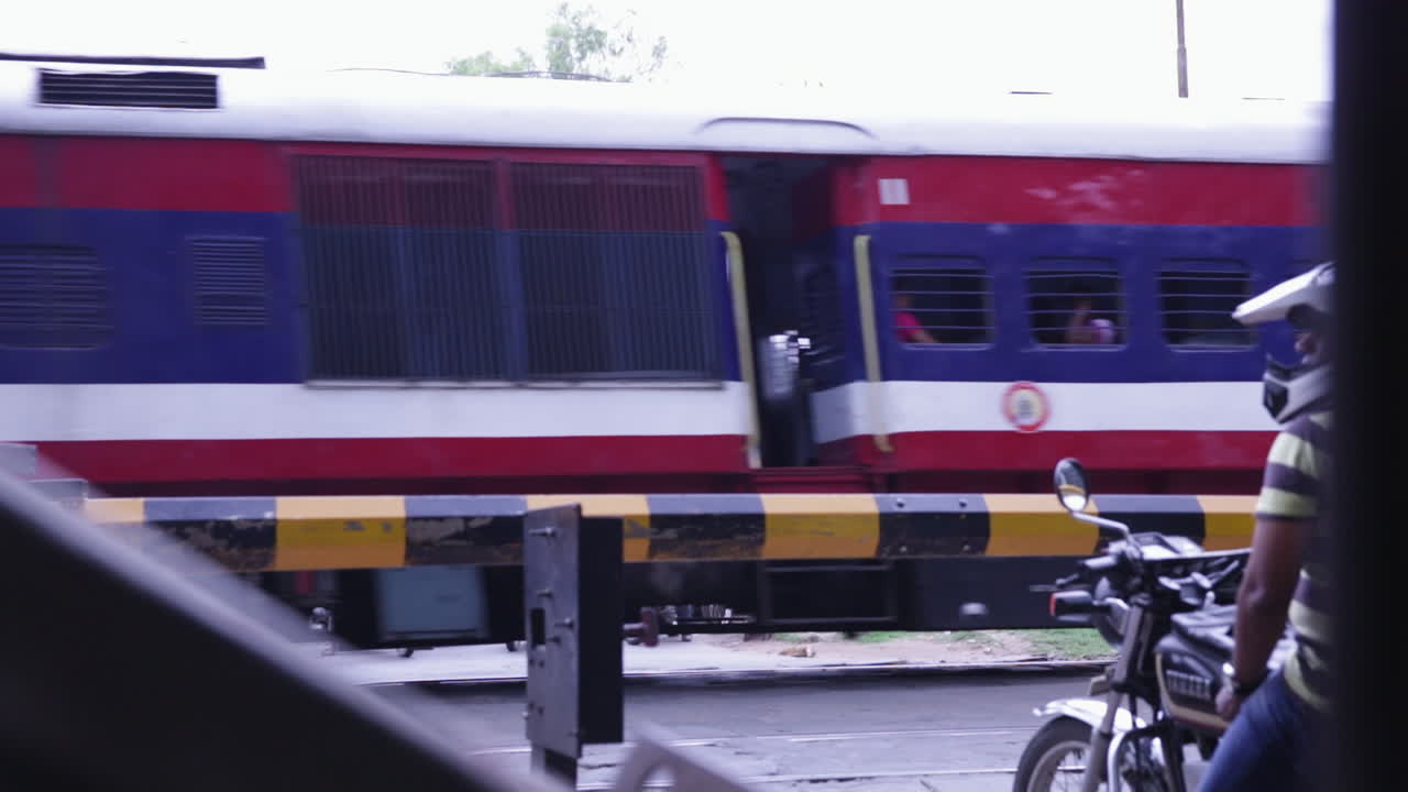 Train passing through busy junction in Bangalore India with people waiting near tracks during the day