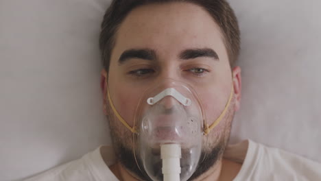 sick man lying on bed breathing through oxygen mask 1