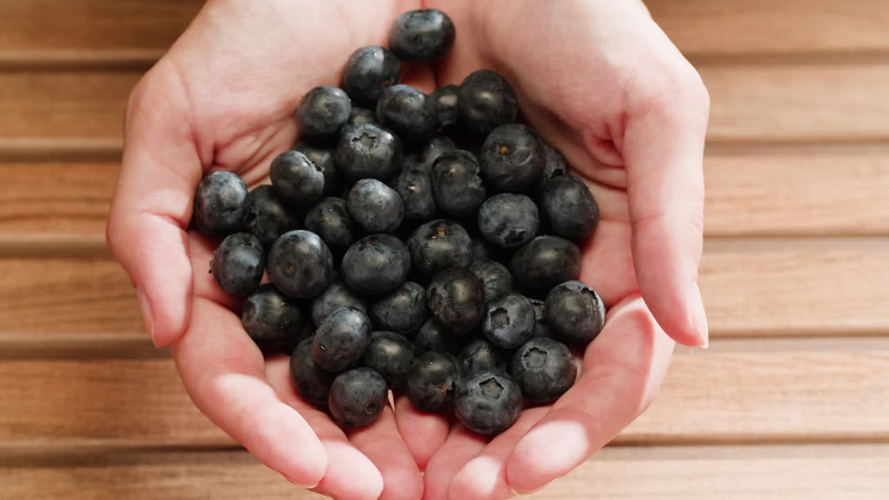 나무 테이블에 손에 블루베리