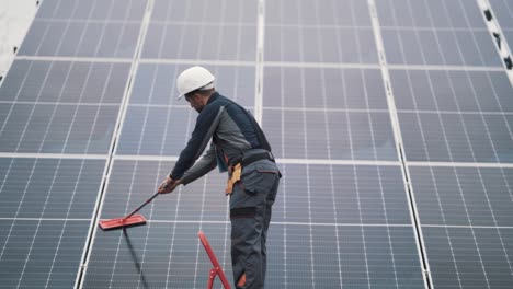 rear view of male worker washing solar panels