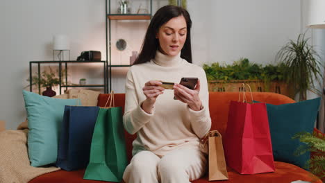 happy shopaholic young woman girl sitting with shopping bags making online payment with credit card