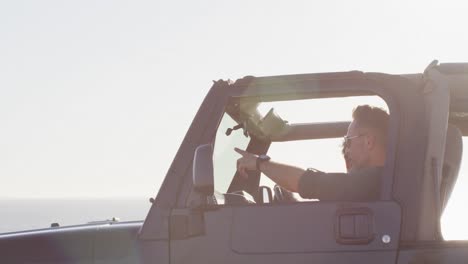 Happy-caucasian-gay-male-couple-in-car-admiring-the-view-and-pointing-on-sunny-day-at-the-beach