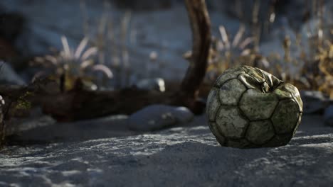 una vieja pelota de fútbol rota arrojada yace en la arena de la playa del mar