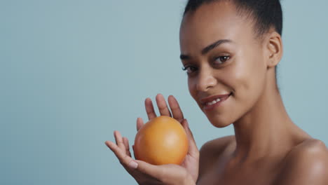 portrait attractive young african american woman holding grapefruit smiling enjoying natural healthy skincare essence beautiful female with perfect complexion on blue background