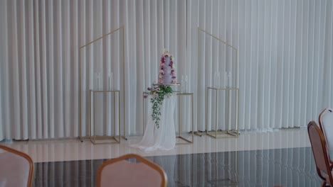 minimalist wedding altar with floral decor and sheer white drapes in a modern indoor setting