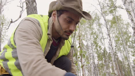 vista inferior de un activista caucásico arando la tierra en el bosque