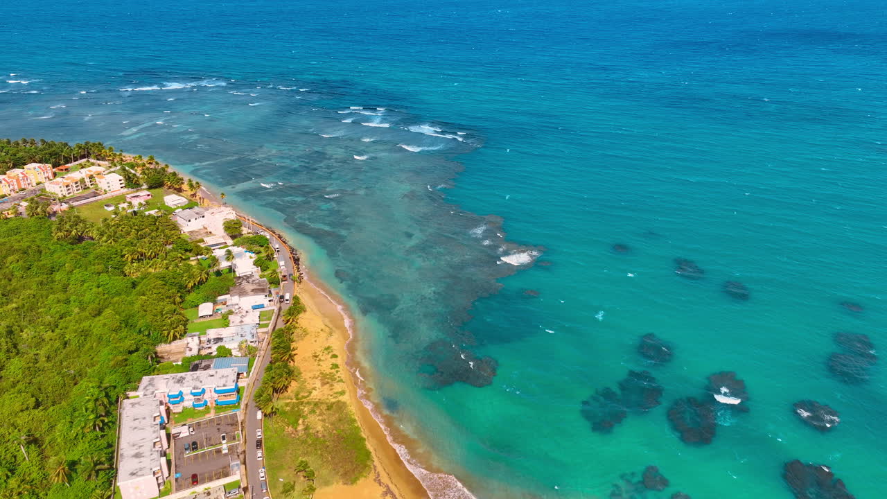 Tranquillo paesaggio acquatico turchese con onde che si infrangono sulla spiaggia sabbiosa. Paesaggio affascinante della costa verde con alcune case. Vista dall'alto. Porto Rico