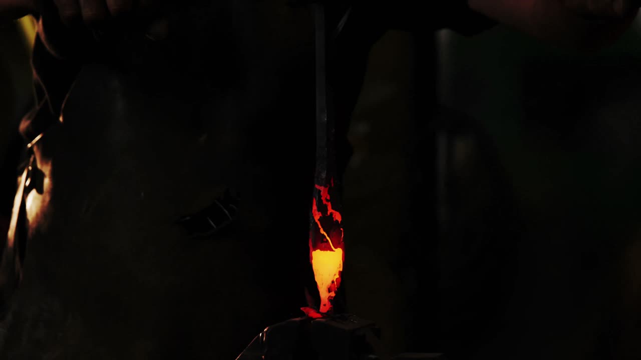 Mid-section of blacksmith holding forged iron rod