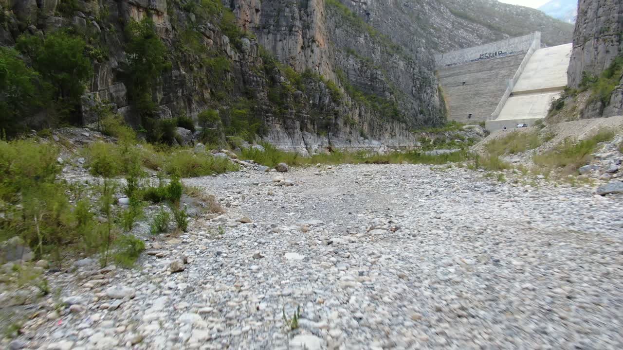 Flying toward hydro-power dam, under the bridge built over dry river on valley of La Huasteca, Monterrey in Mexico