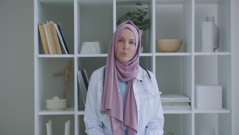 Arab-Muslim-woman-in-hijab-doctor-via-video-conference.-Portrait-of-a-female-Muslim-doctor.-female-healthcare-professional-wearing-scrubs-and-a-hijab-sitting-on-the-stairs-at-a-hospital