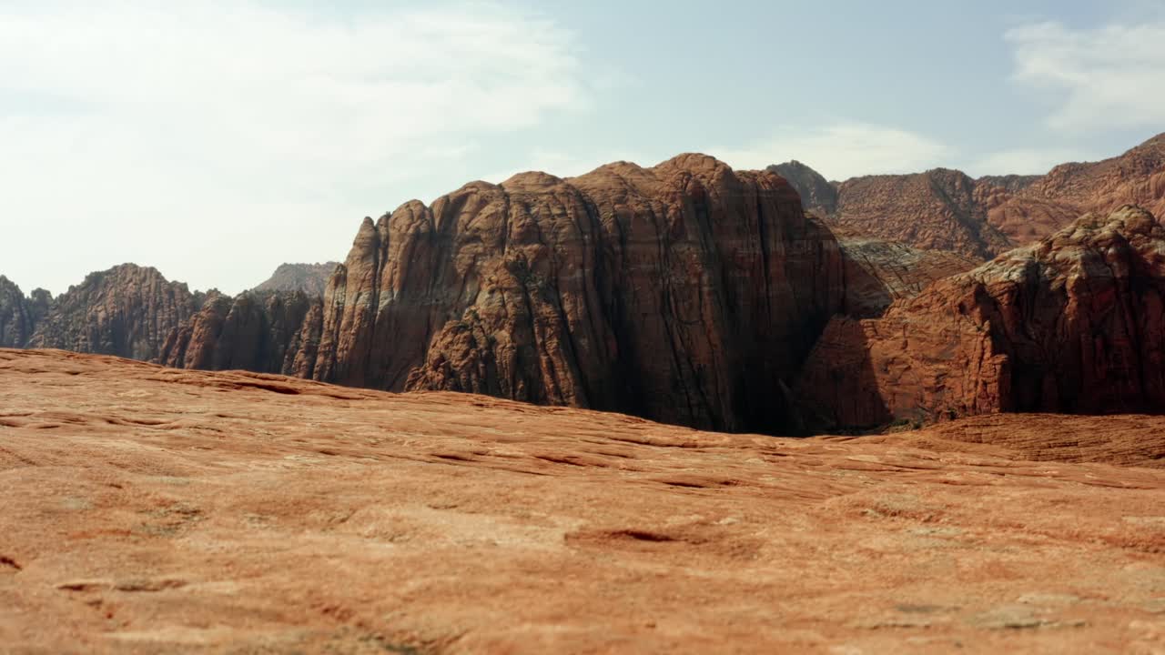 Beautiful aerial drone landscape nature tilting up shot of stunning red rock formations with dried petrified sand dunes below on a hike in Snow Canyon State Park, Utah on a warm sunny summer day