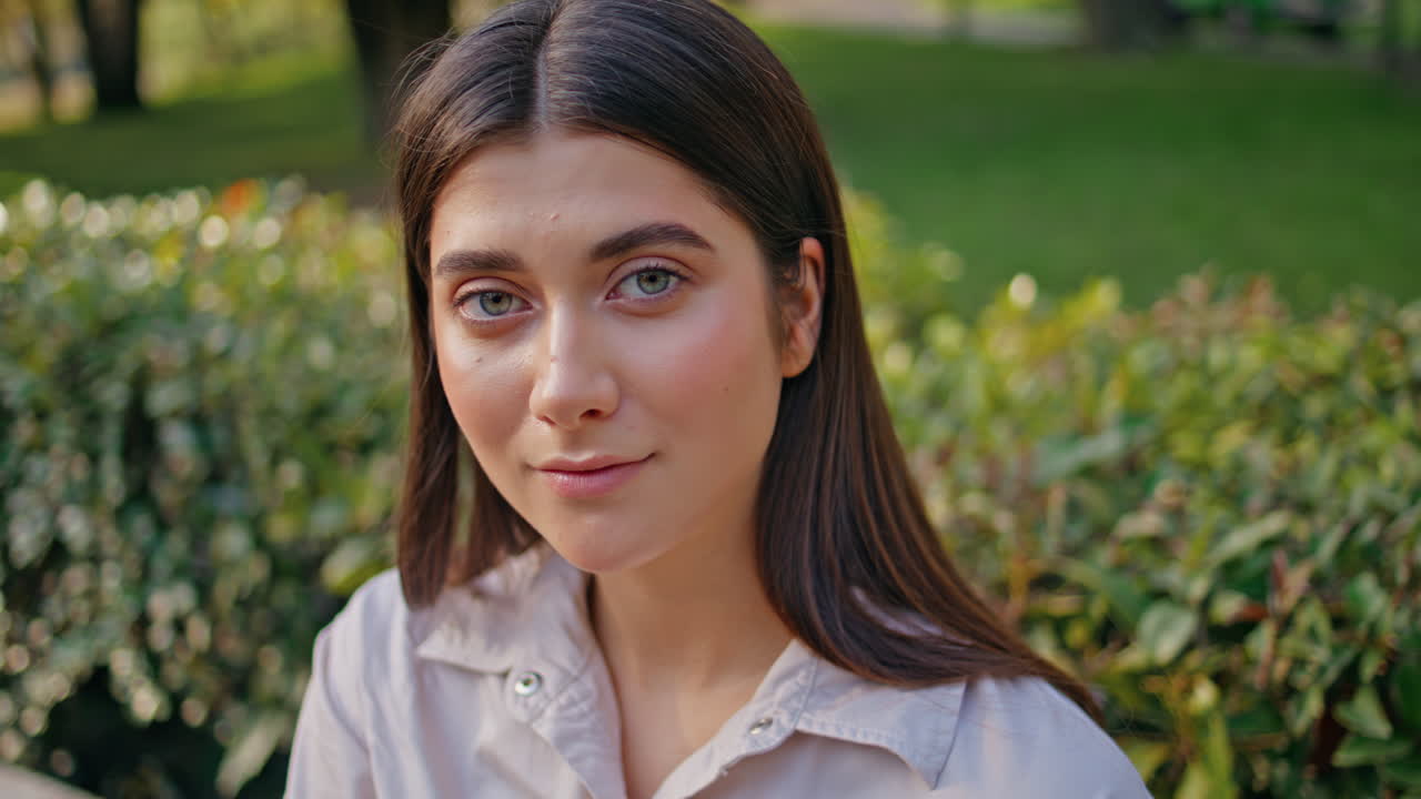 retrato de una mujer reflexiva mirando pensativa sentada en un parque verde de primer plano.