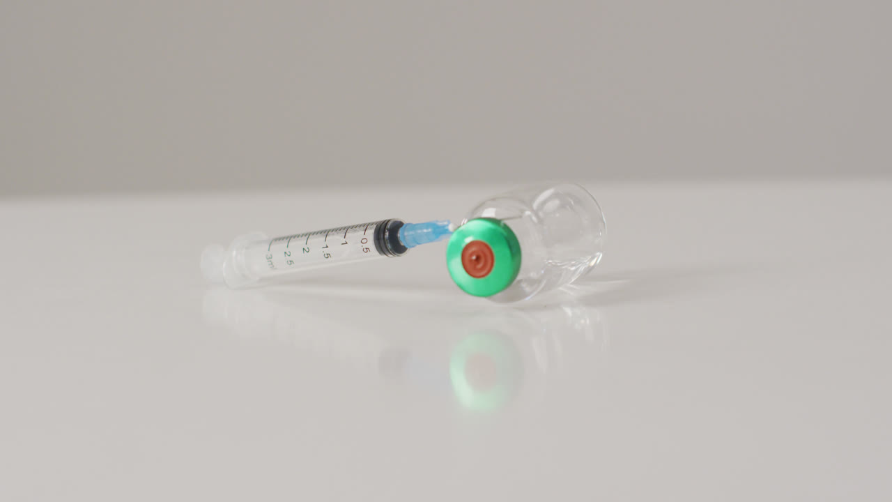 video de un primer plano del vial de vacuna sobre un fondo blanco