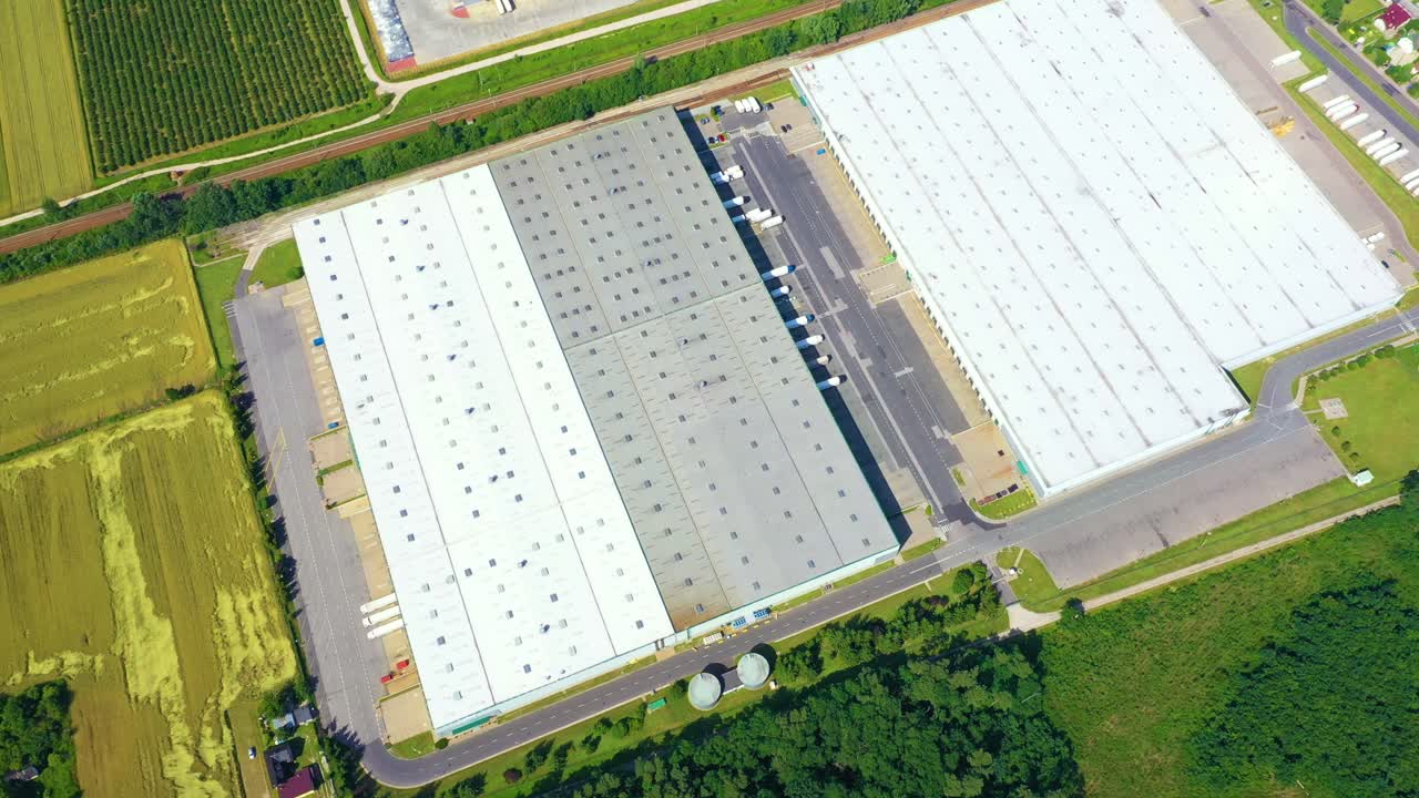 적재 허브가 있는 대형 물류 공원에서 상품을 하역하기 위해 창고 경사로에 화물 트레일러가 있는 세미 트럭의 공중 전망