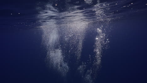 Diver's-bubbles-at-surface-of-the-water-with-a-lonely-fish