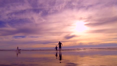 a father and son running out to the ocean during sunset at cannon beach