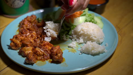 close-up en cámara lenta de una mujer comiendo un plato tradicional de camarón mexicano con arroz blanco y ensalada usando una cuchara