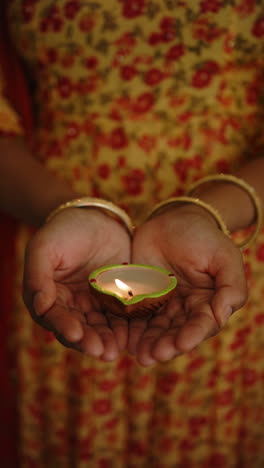 vertical video: holding lit diya, woman celebrating traditional indian festival diwali with joy
