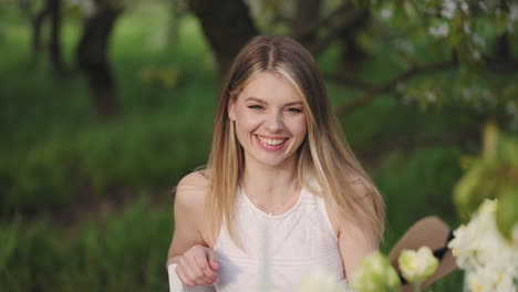 happy-young-woman-is-laughing-sitting-at-table-in-garden-party-family-and-friends-meeting-in-nature