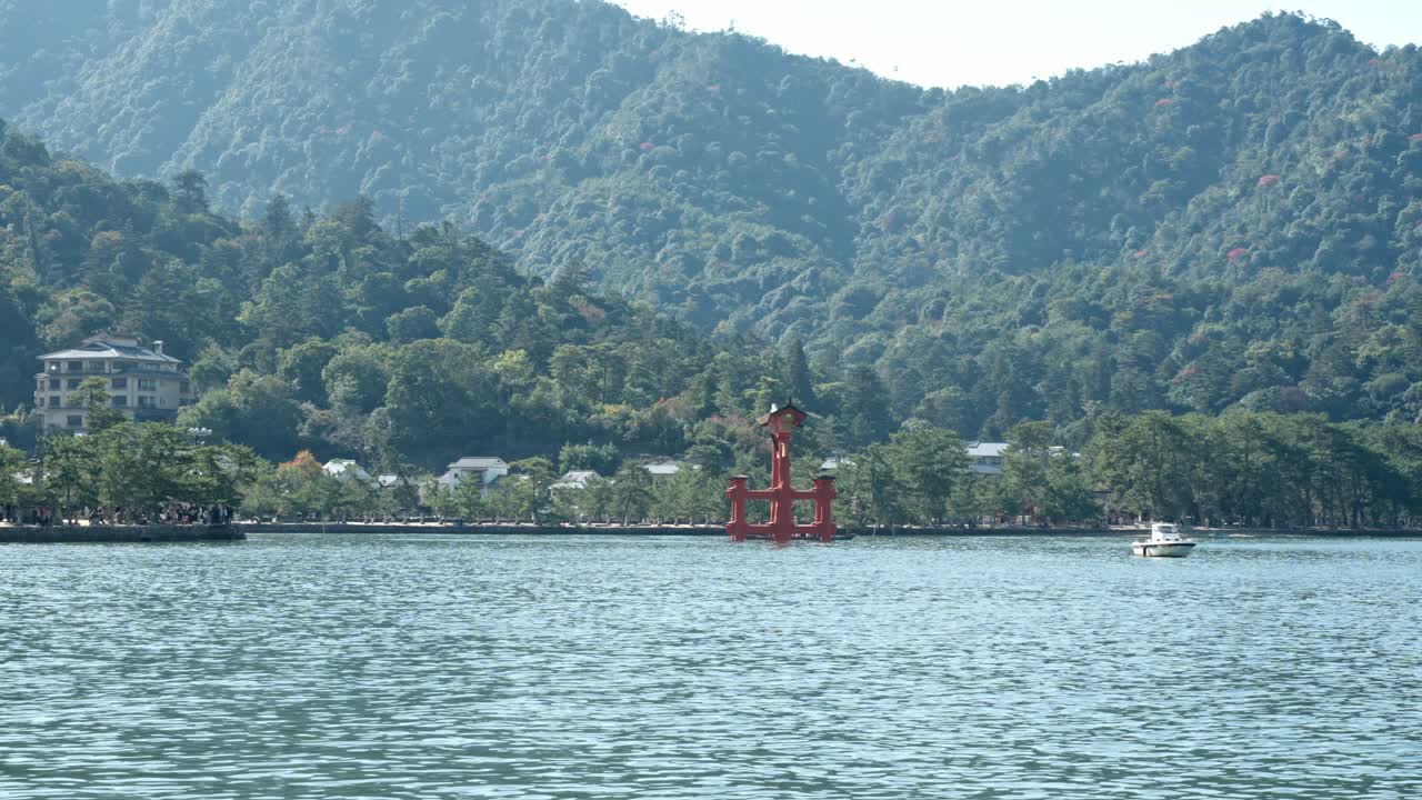 The floating torii gate of Itsukushima Shrine on Miyajima Island, a breathtaking feature of Hiroshima’s rich history, radiates elegance against the island's lush green hills.