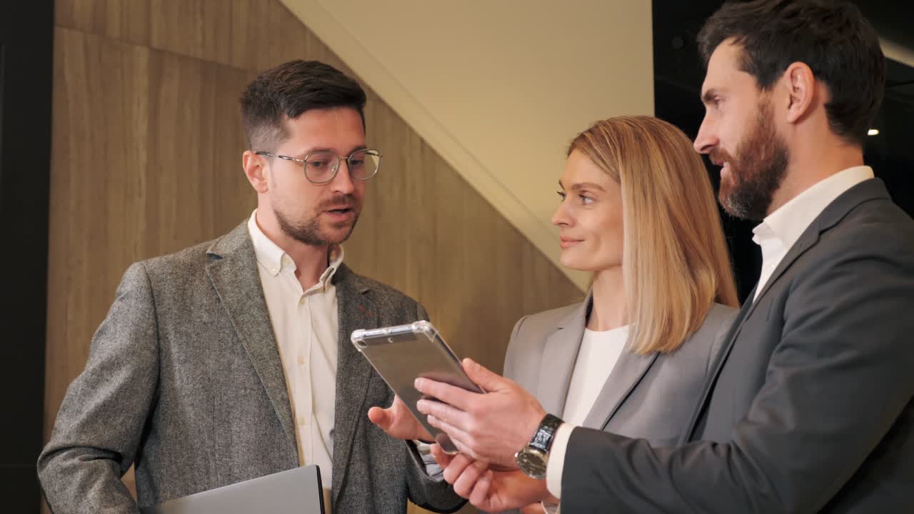 Effective businessman showing project on tablet pc. Executive team business people listening to ceo negotiating discussing results in hall. Stylish company leaders manager counselor talking indoor.