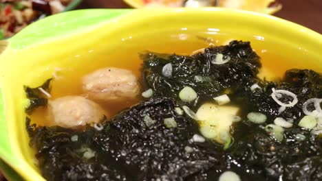 close-up shots of colorful thai rice dishes with minced meat, egg yolk, seaweed soup, and vibrant garnishes, under warm indoor lighting and steady camera angles