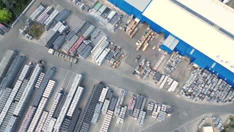 forklift truck driver in warehouse driving between rows of shelving with stacks of boxes and packaging materials