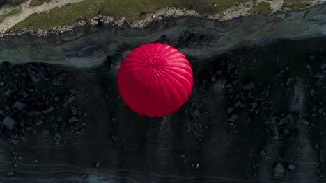 red hot air balloon over cappadocian landscape