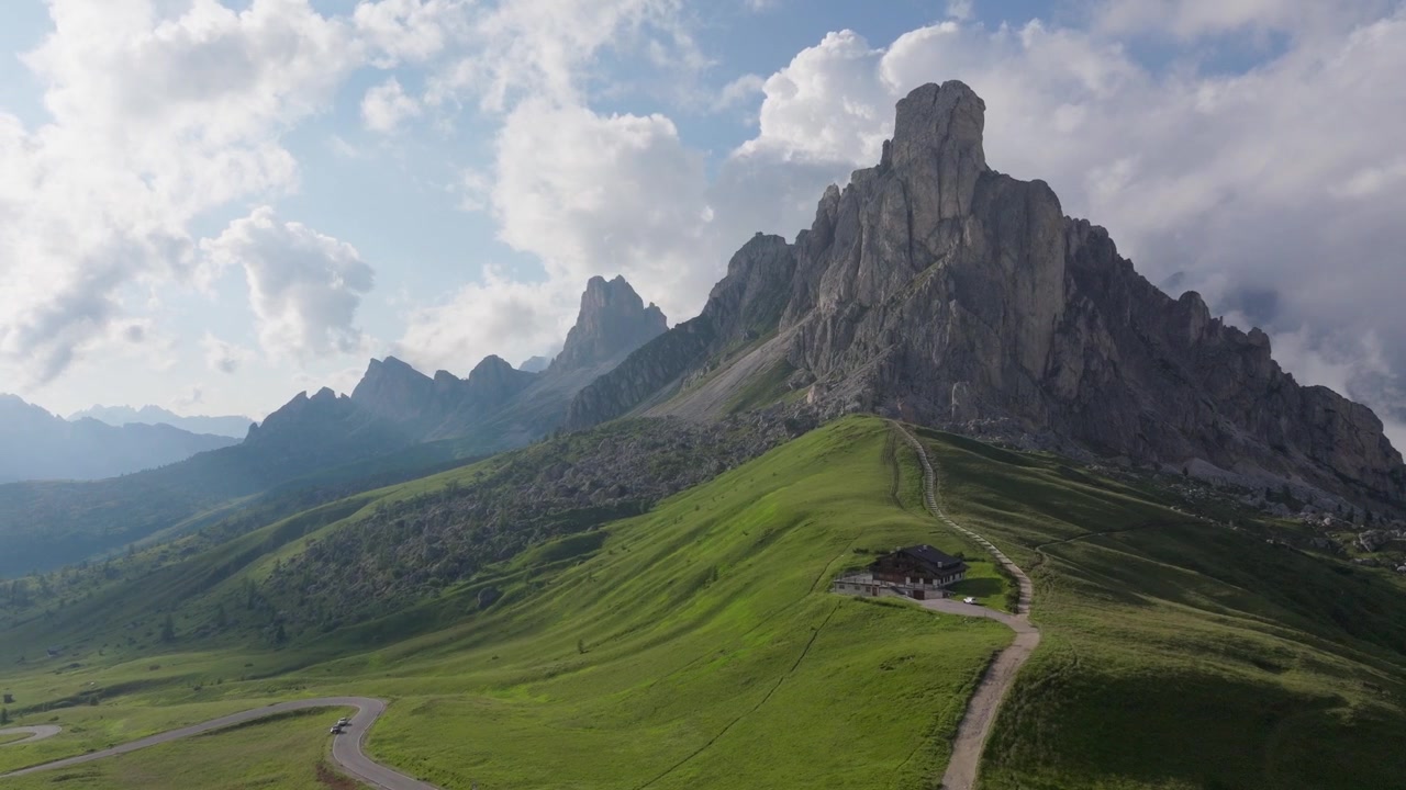 Cảnh quay bằng drone từ trên không về Passo Giau ở Dolomites với con đường núi quanh co, đồng cỏ núi cao và những đỉnh núi đá vôi hùng vĩ dưới bầu trời mùa hè tuyệt đẹp