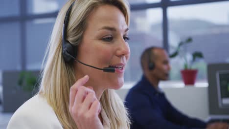 diverse business people sitting using computers talking with phone headsets