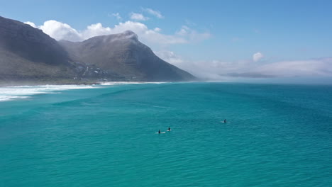 Surfers-waiting-for-waves-in-South-Africa-mountains-in-background-sunny-day