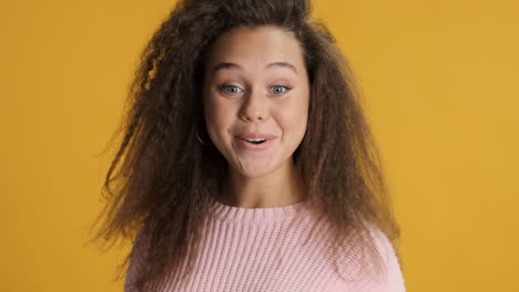 sorprendida mujer caucásica de cabello rizado sonriendo a la cámara.