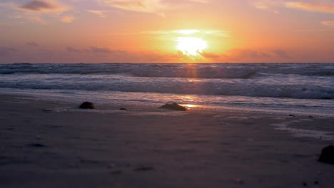 Beautiful-sunset-on-the-background-of-Baltic-sea,-sun-going-beyond-the-horizon-illuminating-water-and-clouds-in-the-sky,-calm-sea-waves,-romantic-mood,-copy-space,-low-wide-shot