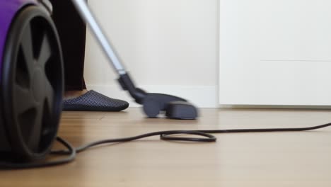 a woman in slippers vacuuming the floor of her home