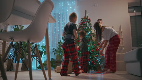 Una-Familia-Con-Dos-Niños-Decoran-Un-árbol-De-Navidad-En-Vísperas-De-Navidad.-Padre-Y-Madre-Con-Hijos-Se-Preparan-Para-El-Año-Nuevo-Y-La-Decoración-Navideña-De-La-Casa.-Imágenes-4k-De-Alta-Calidad