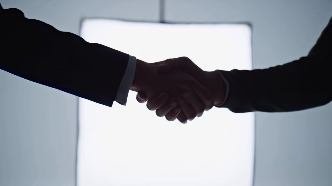 Close-up scene of two people shaking hands at waist level in front of large square diffusion panel, with bright backlight, clear outlines, soft contrast, and professional business mood