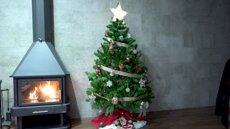 Christmas-tree-decorated-with-star-high-next-to-iron-fireplace-with-fire-plugged-in