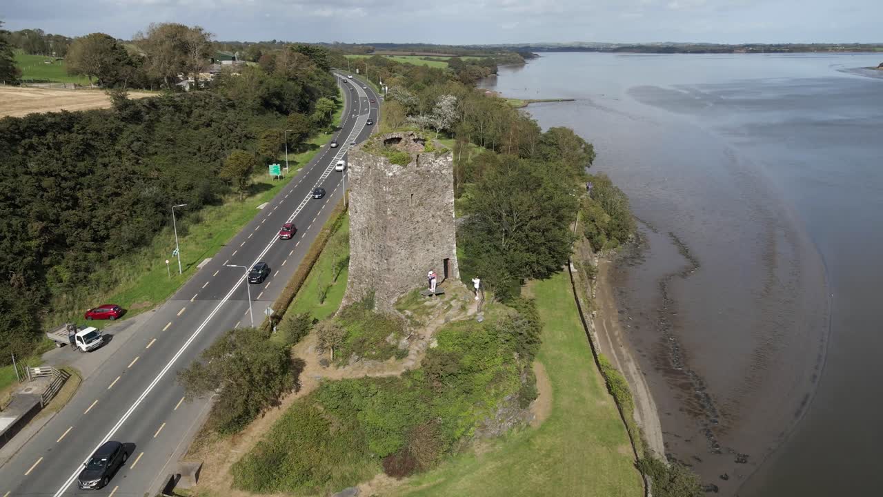 toma de drones de una carretera transitada y ruinas de un antiguo castillo con un amplio estuario de río en el fondo