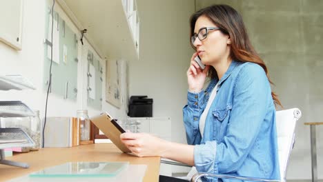 mujer ejecutiva usando una tableta digital mientras habla por teléfono móvil