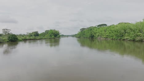 Río-Tranquilo-Que-Fluye-A-Través-De-Una-Exuberante-Vegetación-Bajo-Un-Cielo-Nublado-En-Florencia,-Colombia