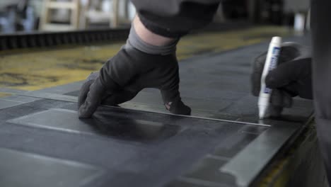 industrial-worker-drawing-lines-with-white-marker-pen-on-rubber,-closeup-slow-motion