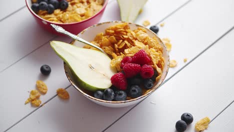 Goldene-Cornflakes-Mit-Frischen-Früchten-Von-Himbeeren,-Blaubeeren-Und-Birne-In-Keramikschale