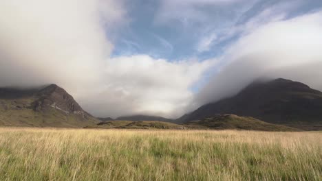 grassy moorland in from of dramatic scottish mountains and a valley