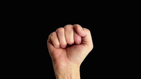 close up shot of a male hand holding up a classic power or fist sign, against a plain black background