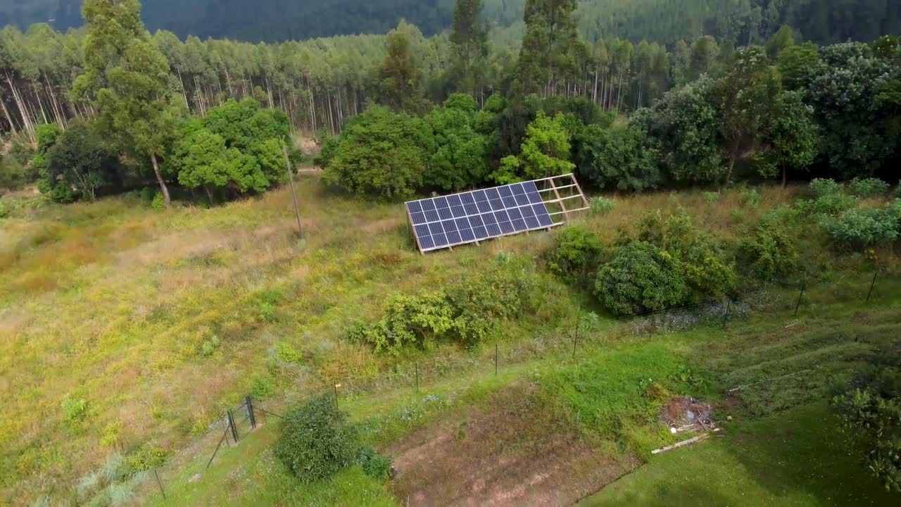 Droneoptagelse af solcelleanlæg på åben mark, der forsyner en gård med strøm.