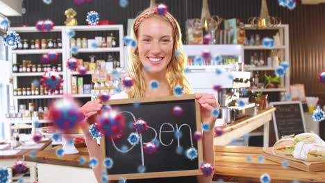 Animation-of-virus-cells-over-happy-caucasian-waitress-with-open-sign