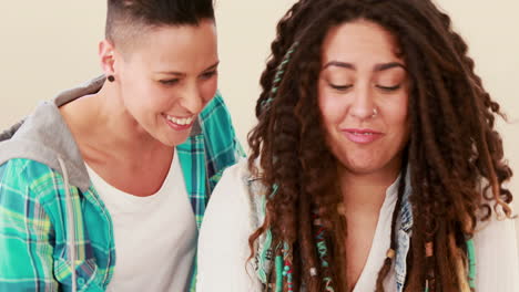 una pareja de lesbianas sonrientes usando una computadora portátil en la cocina
