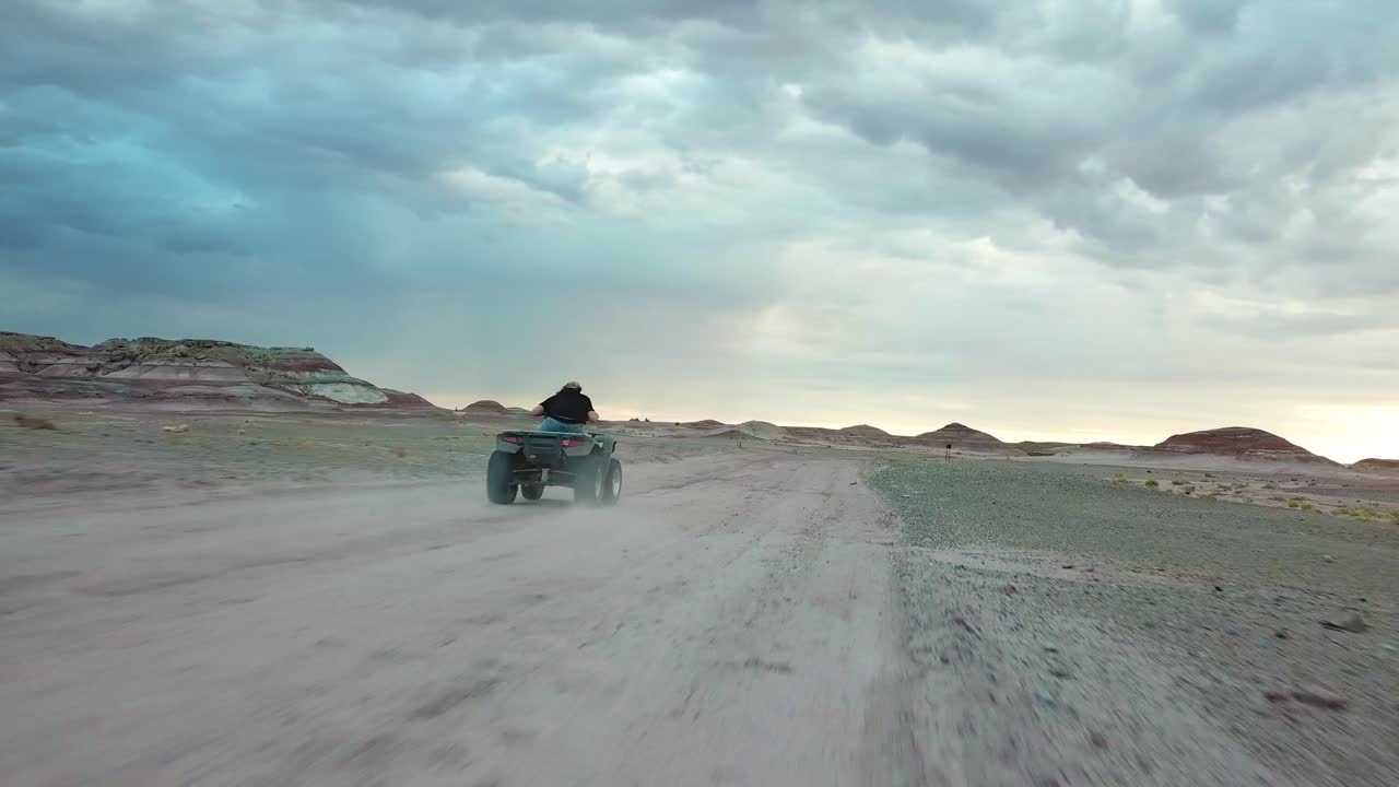 Man Driving ATV Vehicle on Dusty Road in Twilight, Aerial View. Apocalyptic Scenery in Utah Desert USA