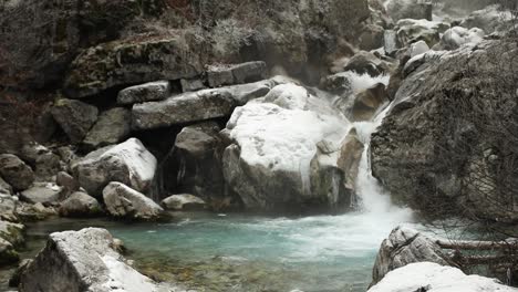 peaceful scenic view of water stream flowing through big cliffs covered in ice and snow