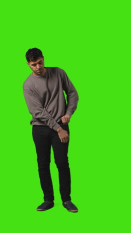 Vertical-Video-Full-Length-Shot-Of-Man-Looking-At-Text-Message-On-Mobile-Phone-Standing-Against-Green-Screen-4